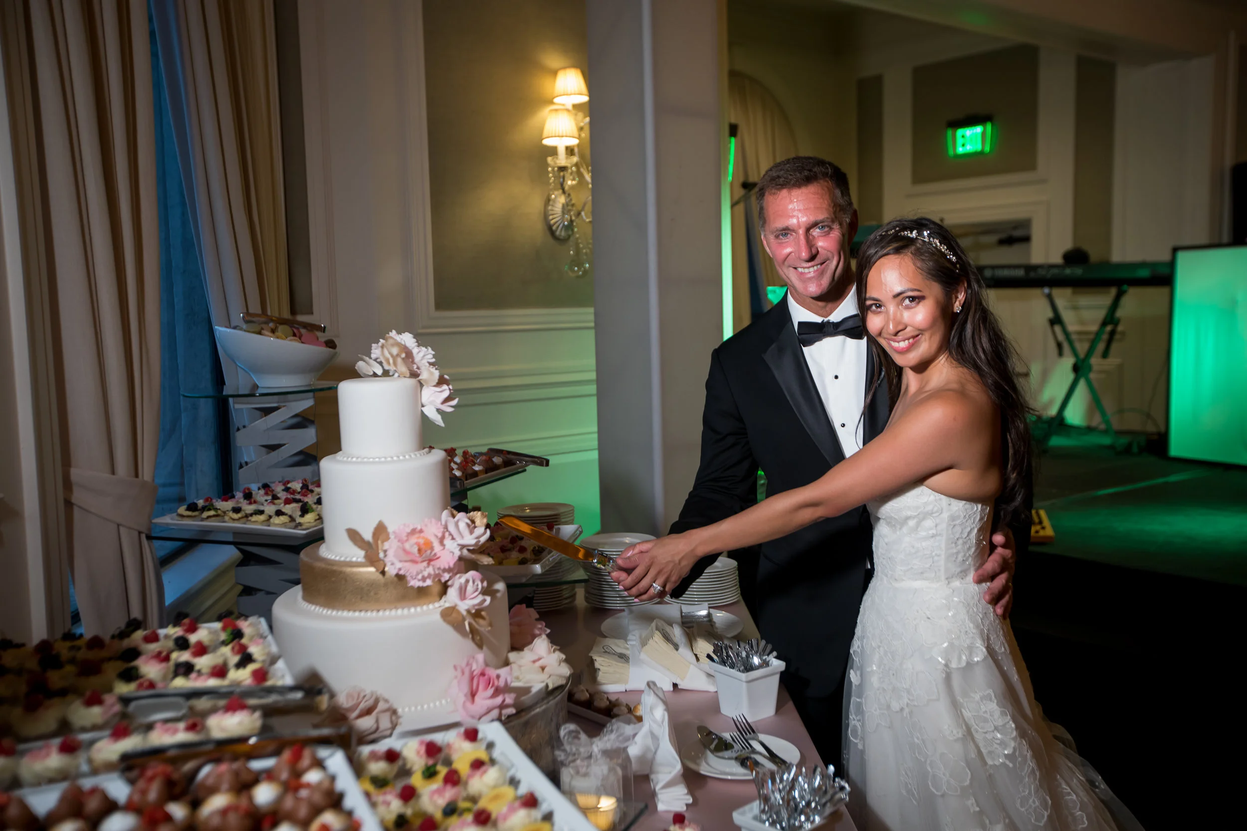 A bride and groom cutting a wedding cake together at their reception.