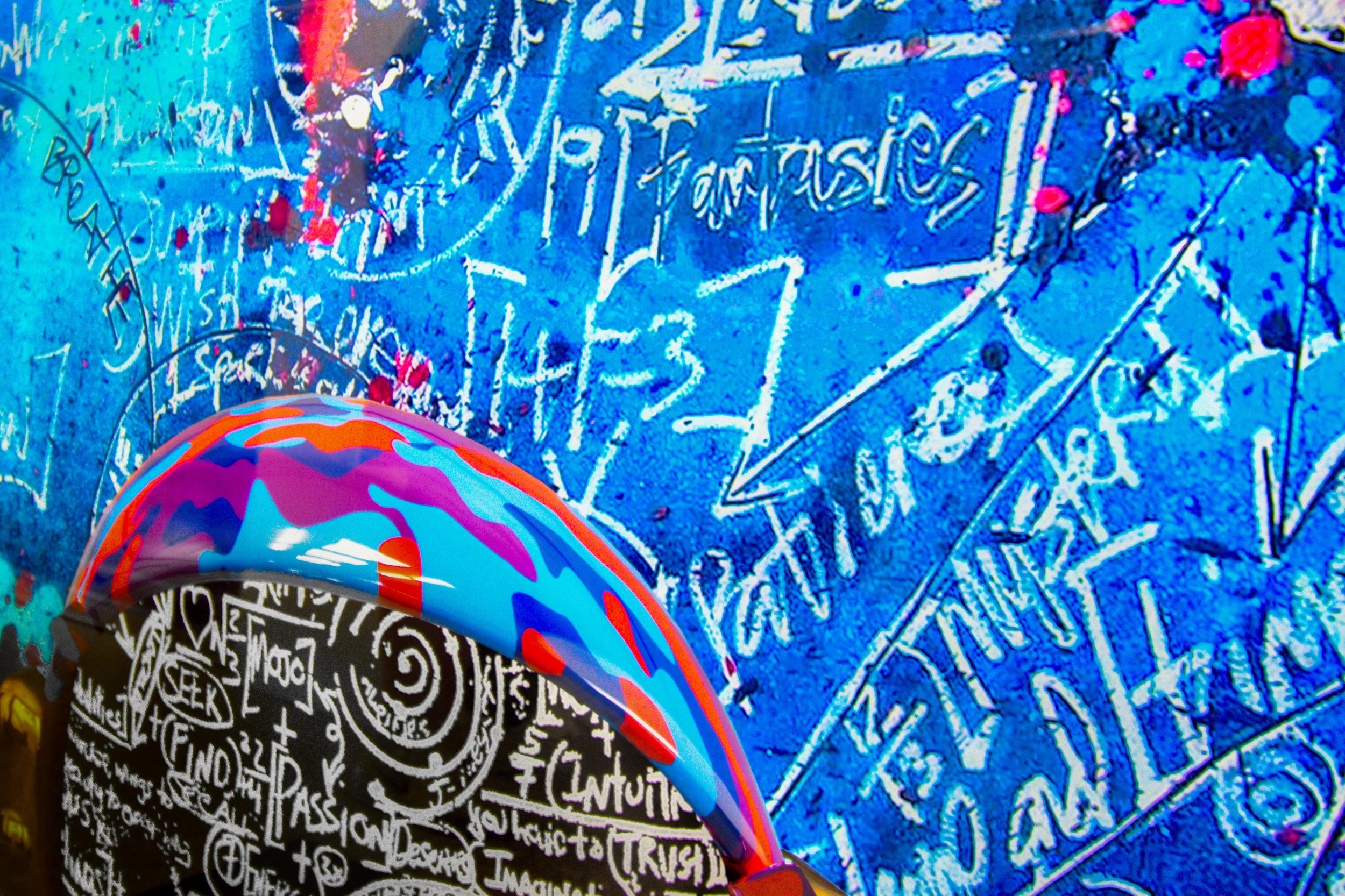 Colorful graffiti wall with abstract art and handwritten words in vibrant blue, black, and multicolor paint splatters.