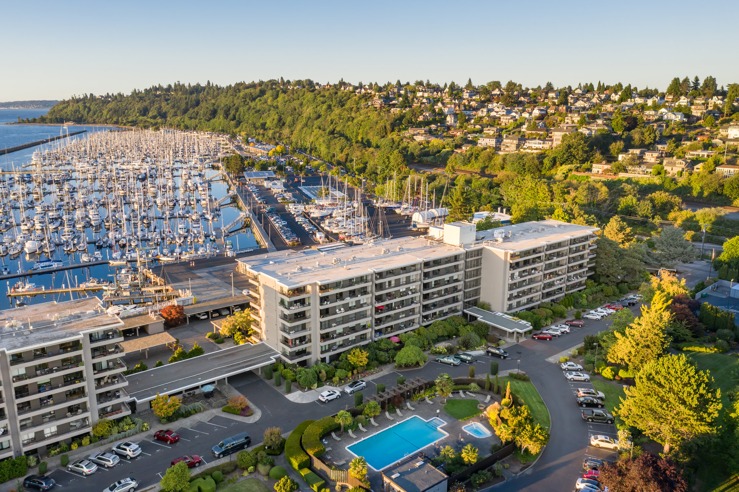 aerial drone shot of condo with pool and marina beyond