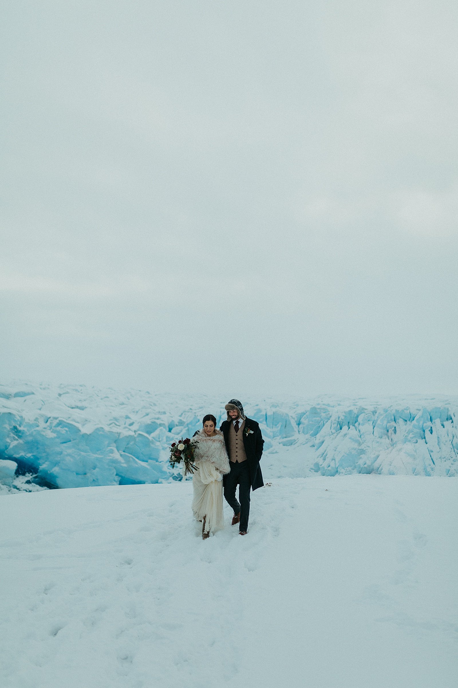  Bride and groom walking along a winter mountain in Anchorage, Alaska 