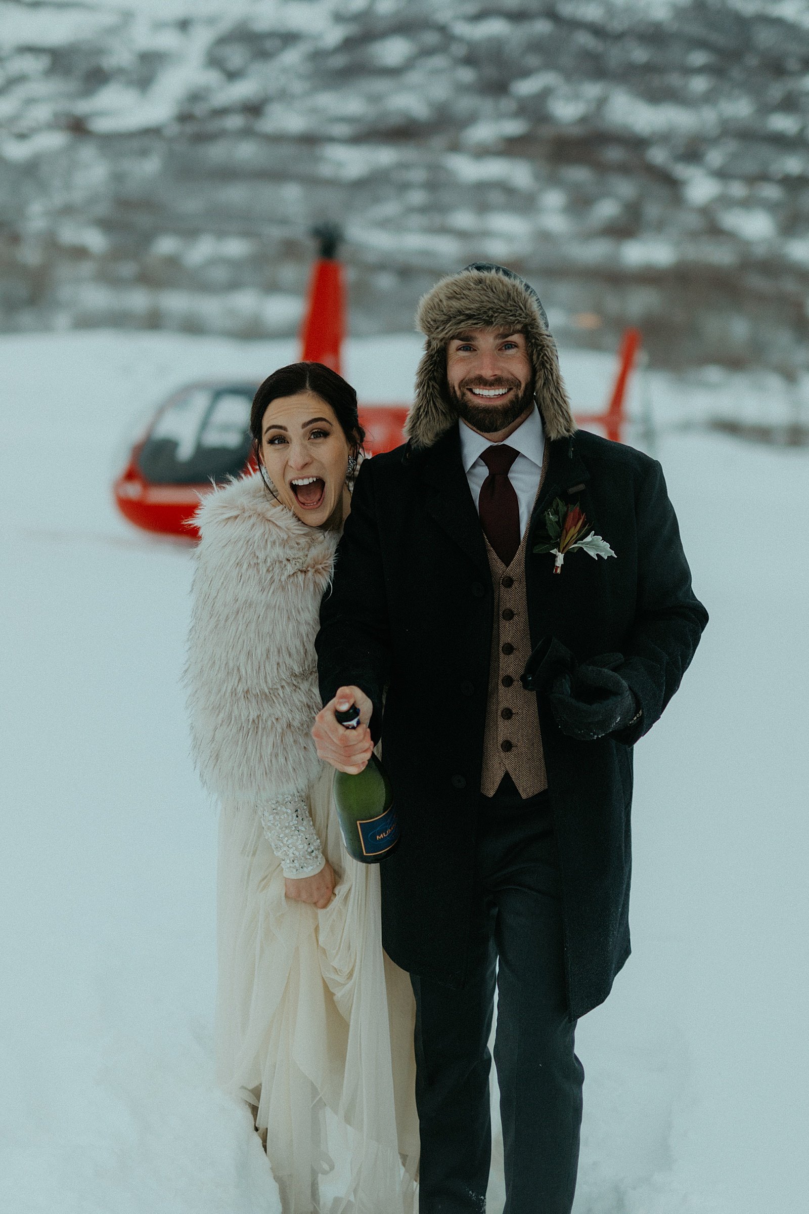  Bride and groom in front of red helicopter on a mountain for a glacier adventure elopement 