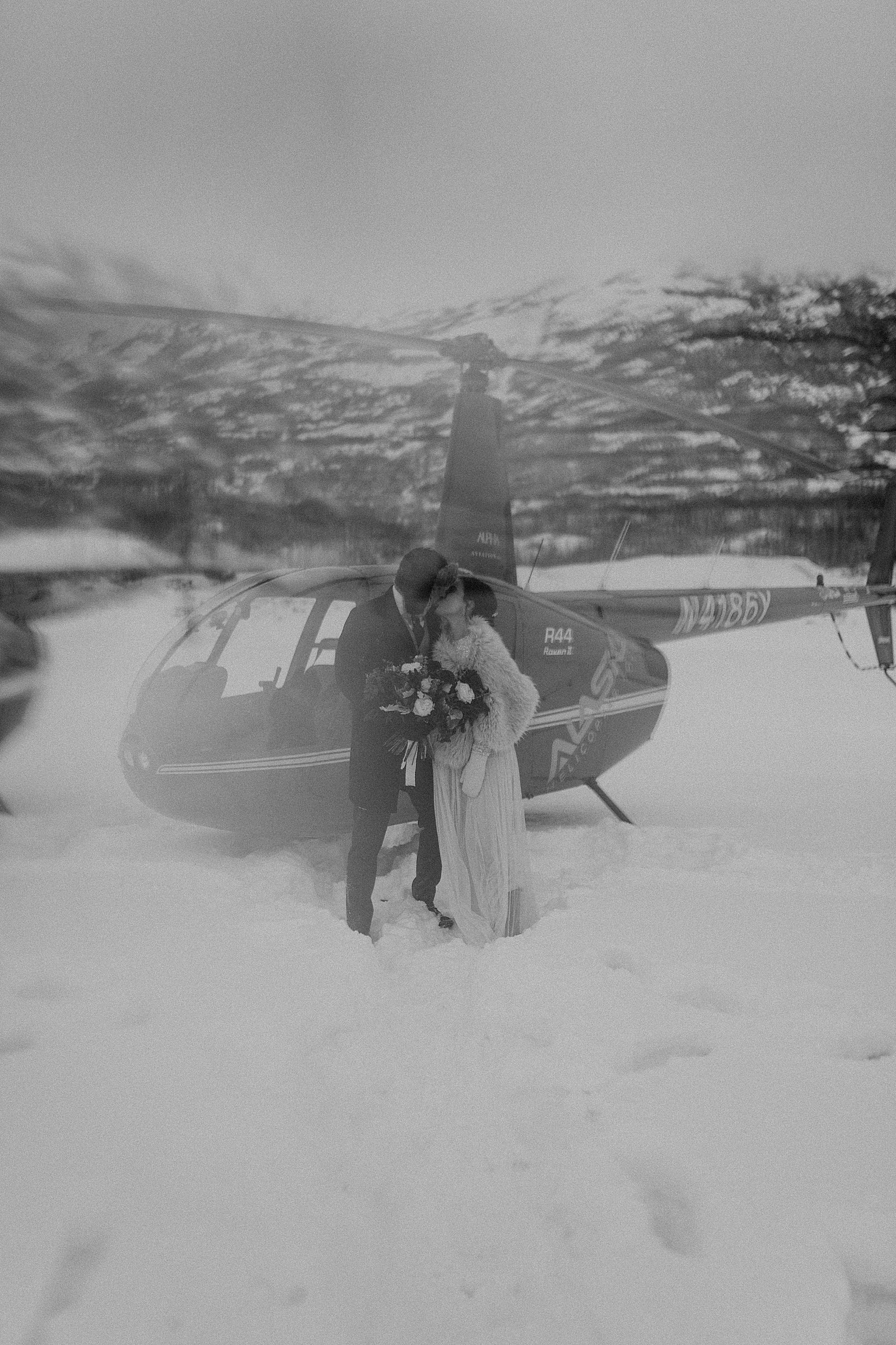  Bride and groom embracing in front of a helicopter by Anchorage wedding photographer 