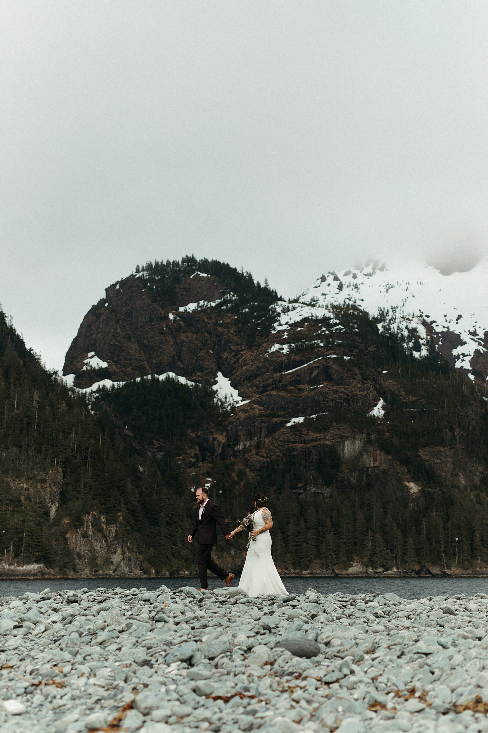  Newlyweds walking along a beach after their ceremony by an Alaska wedding photographer 