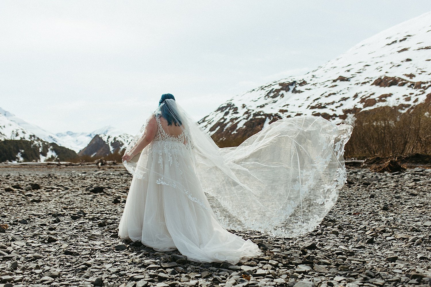  Bride standing in front of Alaska mountains at an intimate beach elopement in Girdwood 