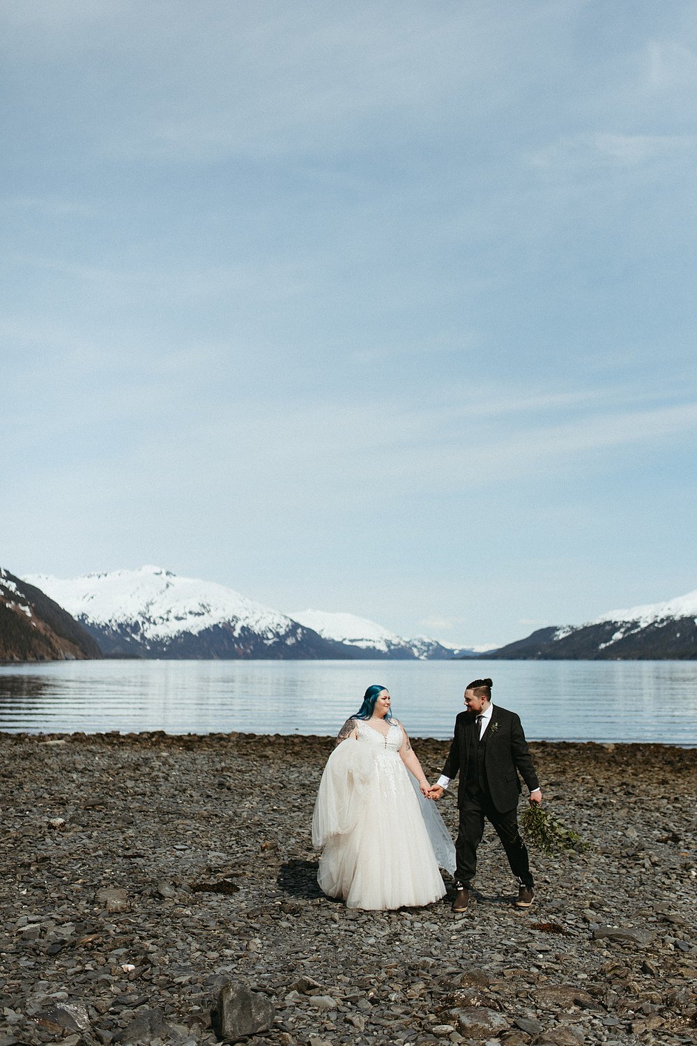  Bride with blue hair and groom walking next to mountain lake by Rachel Struve Photography 