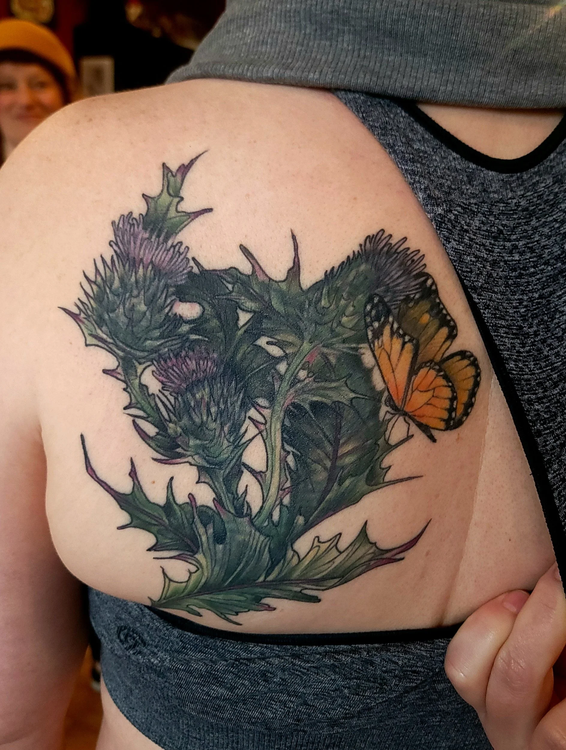 Tattoo of thistle plant and butterfly on upper back shoulder blade .Covering up a old Pacific Northwest killer whale design...after cover up