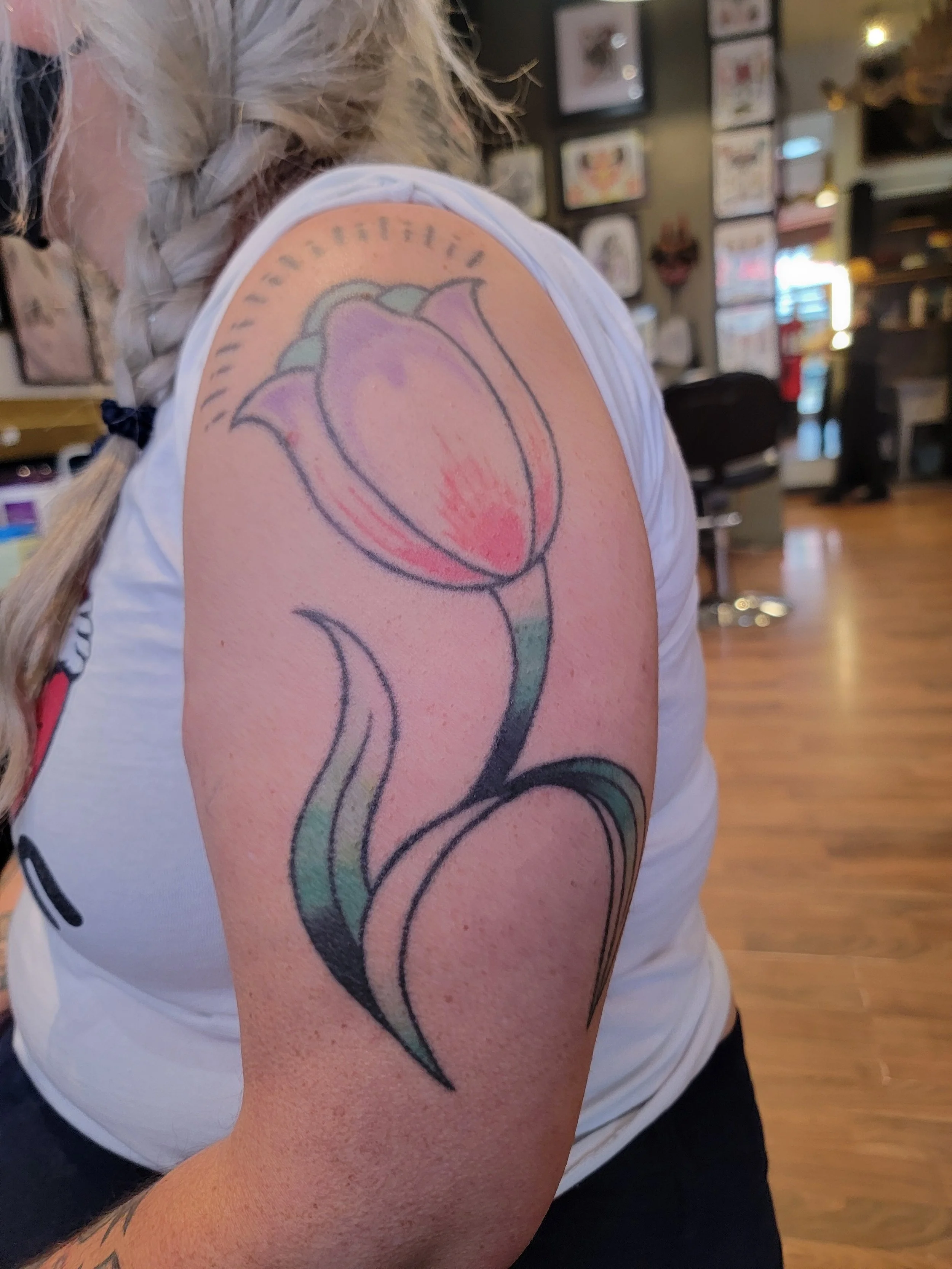 Before cover up of a bold traditional tulip that the client was over how much of their arm the design took up and wanted it covered with something that reflected things they love. The queen of hearts, their Chevellle and adding in an ode to the old t
