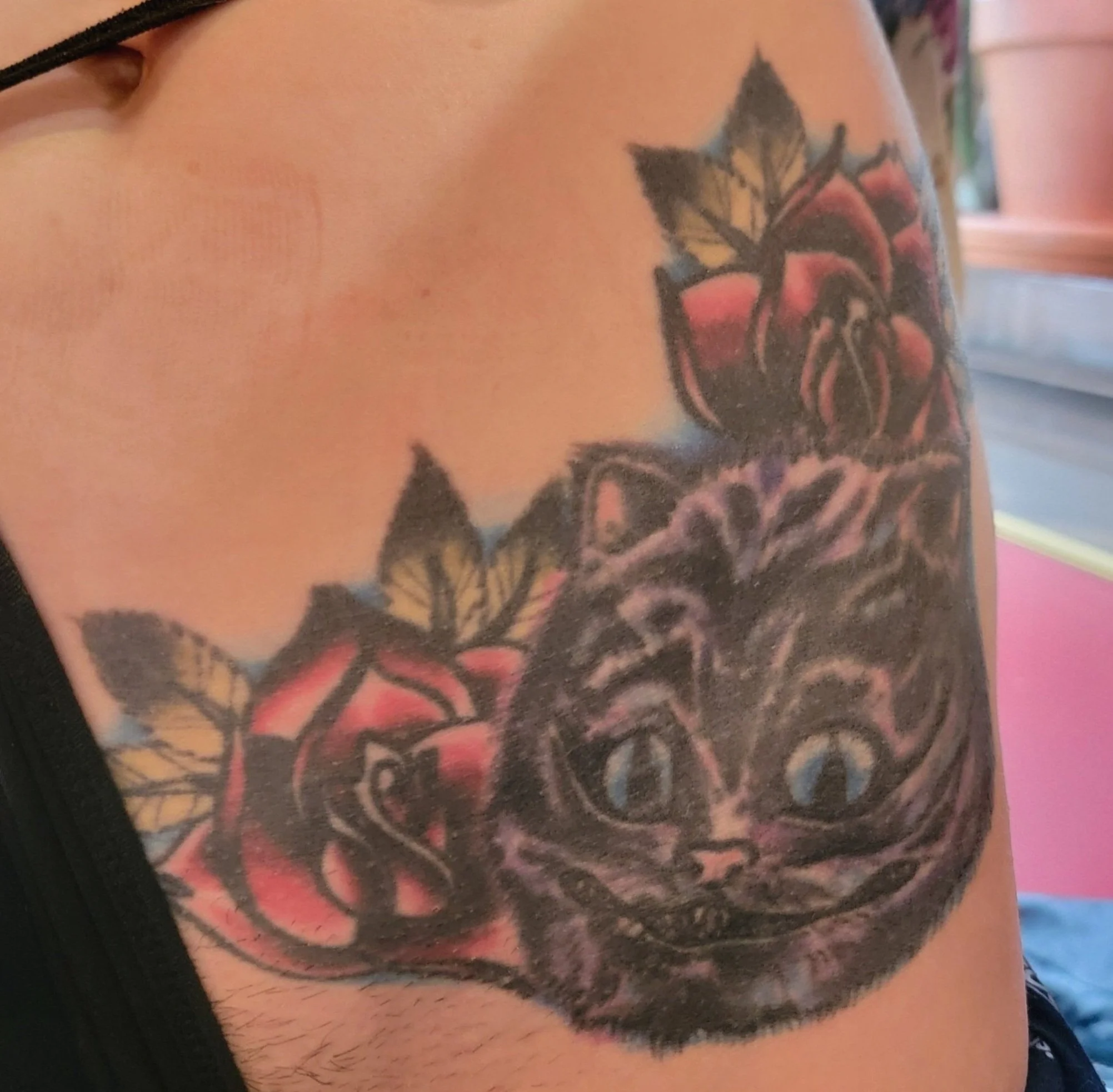 Before cover up of a cheshire cat on the front hip. This was already gone over by a previous tattooer who added color and the flowers to the existing cat tattoo. I plan on covering it all with flowers to not make the design any bigger than the existi