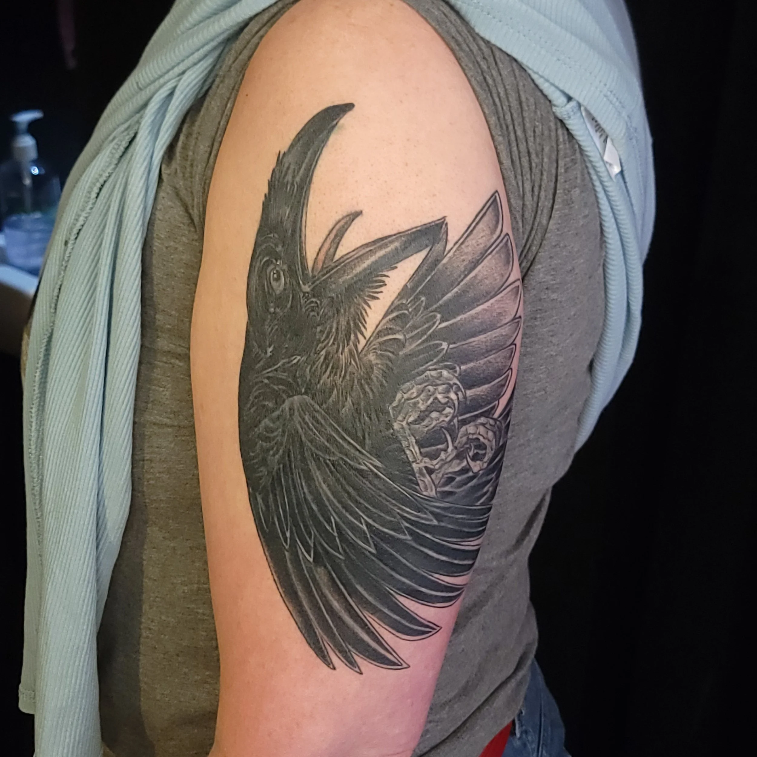 Black crow tattoo on upper arm cover up of of a crow with an new crow. Healed