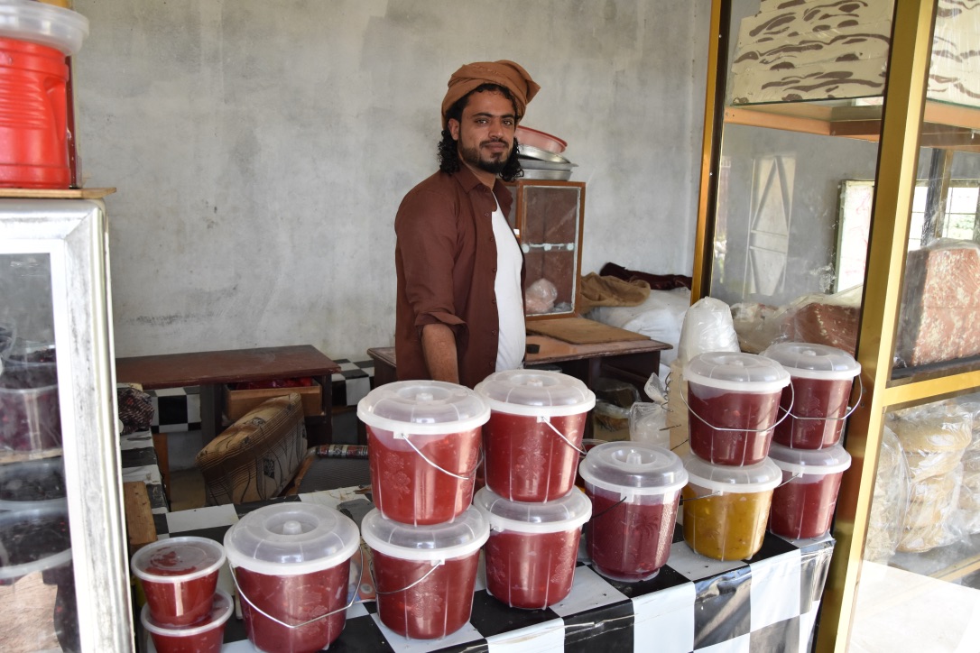 A Yemeni man stands in front of some traditional desserts
