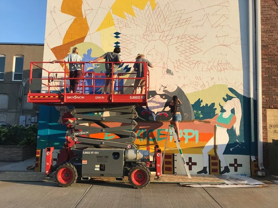 The ascent begins. Artists use the lift provided by partner Midwest ReadyMix to reach the upper portions of the wall.
