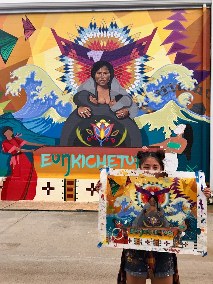  Lead muralist Reyna Hernandez holds up the color study maquette for comparison to the mural.  