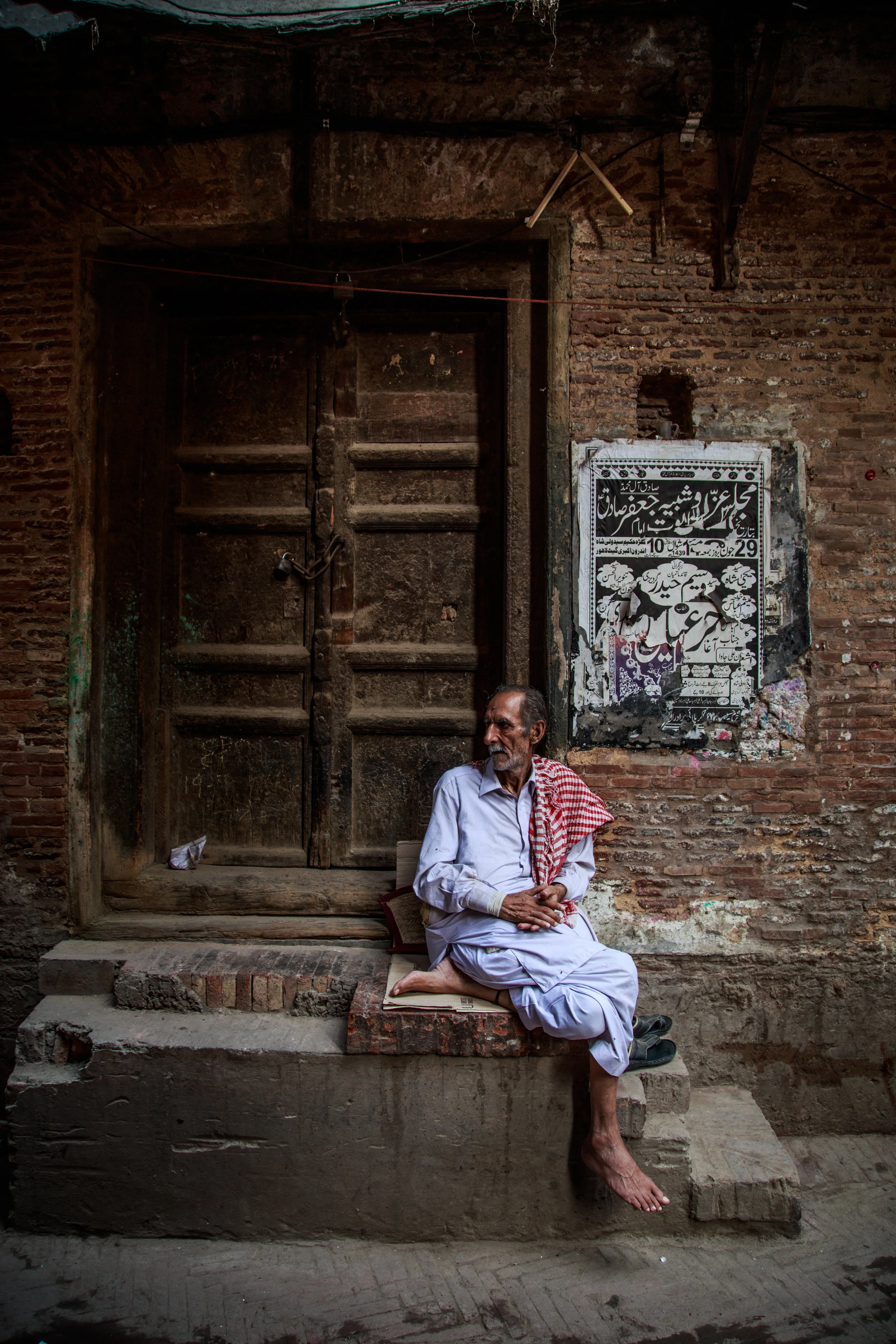 man sitting in front of door, man in ethnic clothes, photos of pakistan, street photography in pakistan, photography for sale, street photography for sale, travel photography