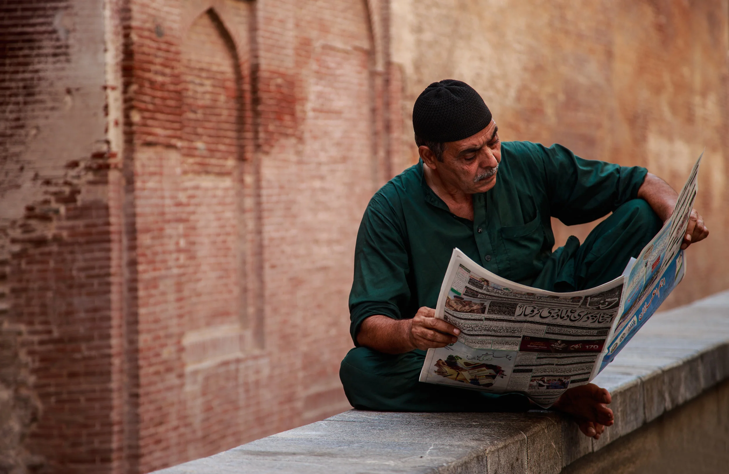 man reading newspaper on the wall, photos of pakistan, street photography in pakistan, photography for sale, street photography for sale, travel photography