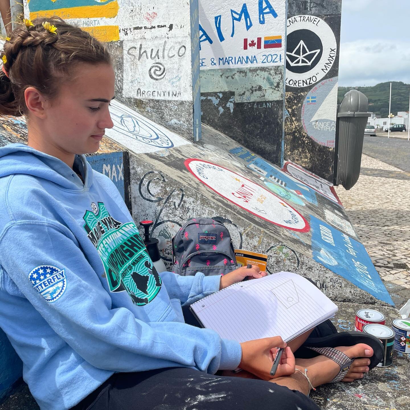 An essential part of arriving in Horta from a transatlantic sail is to commemorate by painting your boats name and crew names on the wharf. Today we began the process by claiming a spot, painting a White canvas, and doing some initial design work. St