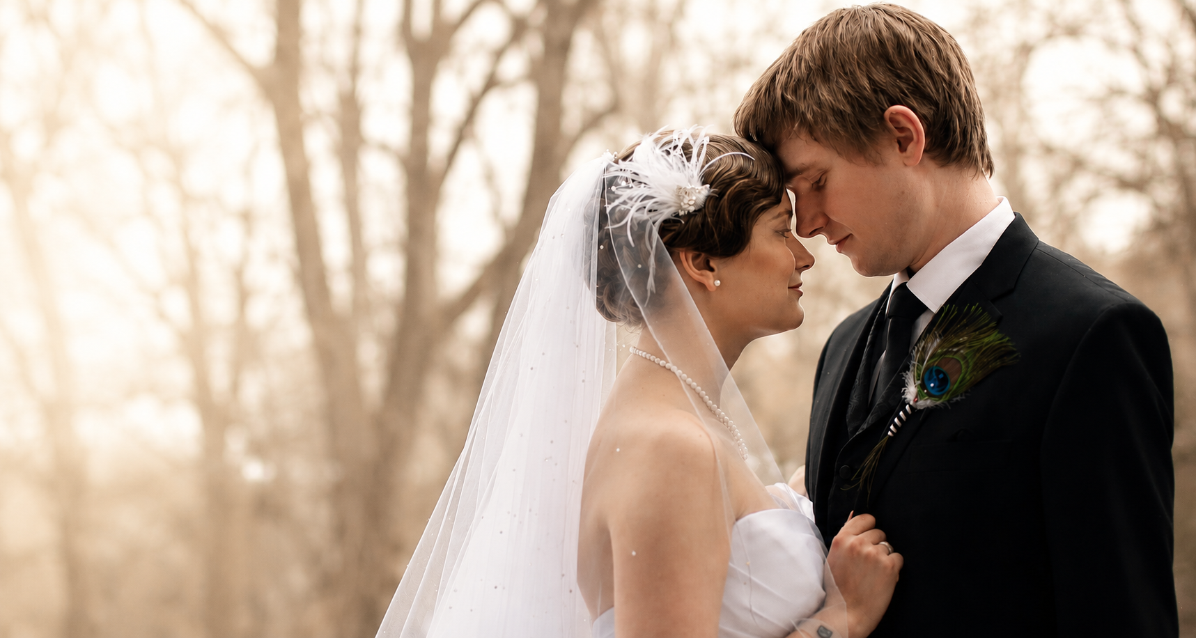 Romantic outdoor wedding portrait of a bride and groom embracing in soft natural light, showcasing an elegant and intimate wedding day moment.