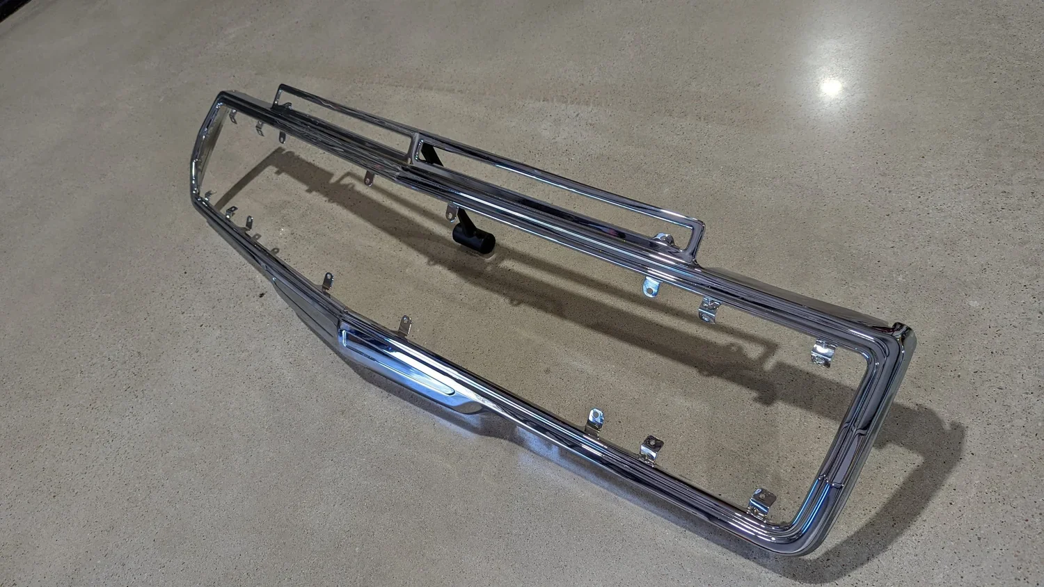 Close-up detail of chrome Grand Wagoneer grille surround showing restored aluminum surface