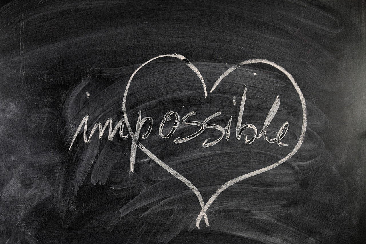 a chalkboard with the word impossible written on it. a heart is drawn around the possible - how coaching works - making the impossible possible
