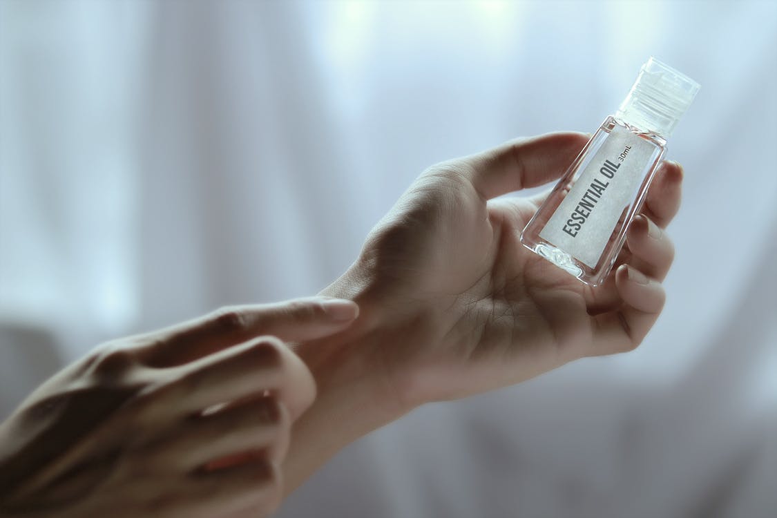A pair of hands holding a small bottle of essential oil - how to look after your needs on holiday with chronic illness