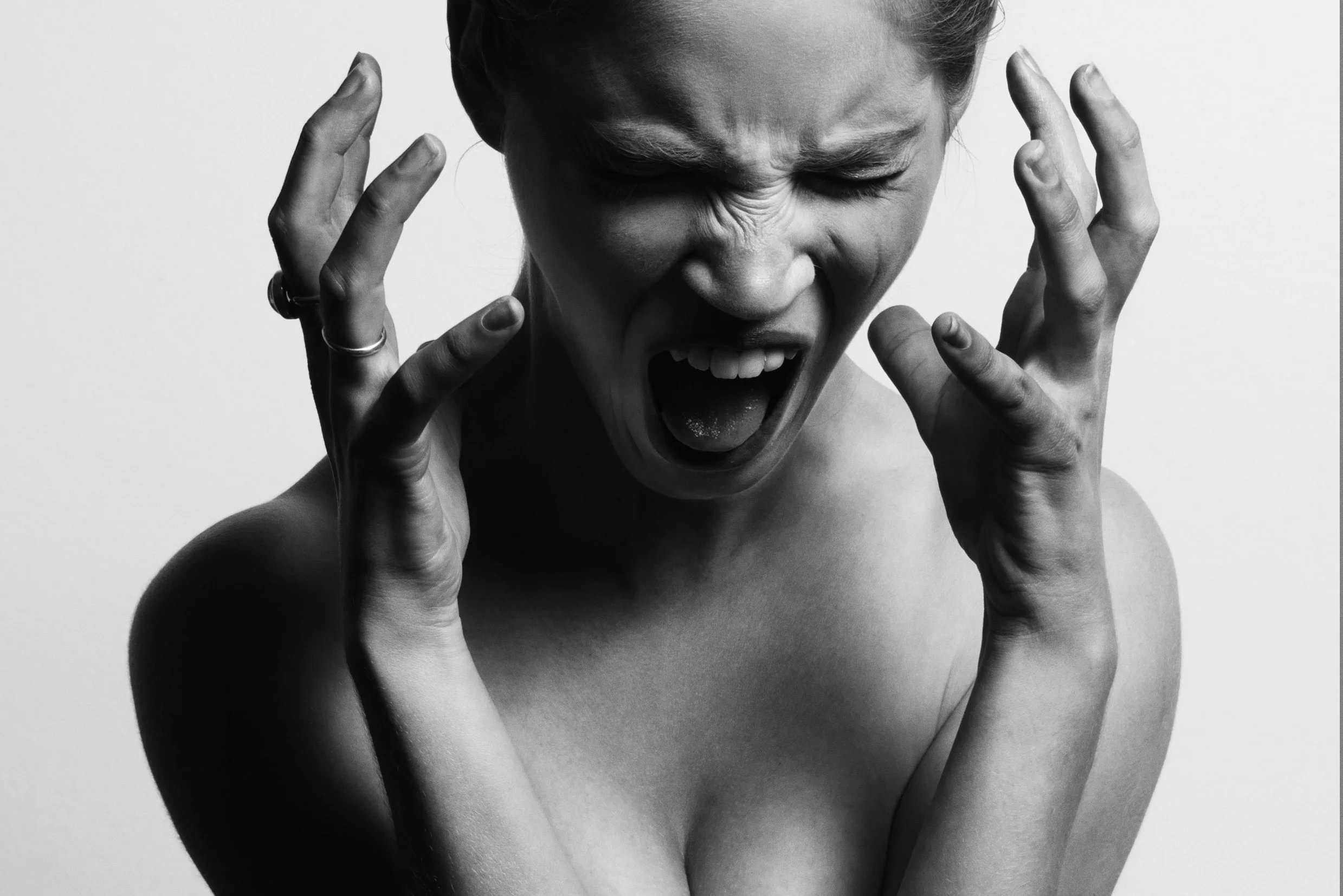 greyscale photo of a woman screaming with stress, her hands raised to her face - - workplace wellbeing workshops - stress management and resilience workshops