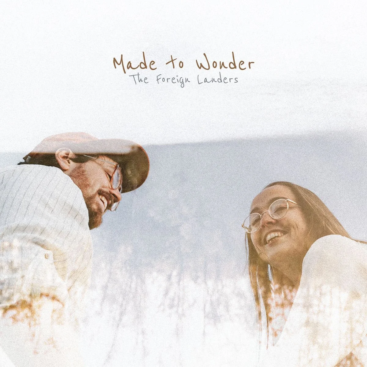 A man and woman smiling at each other outdoors, with the text "Made to Wonder The Foreign Landers" above them.