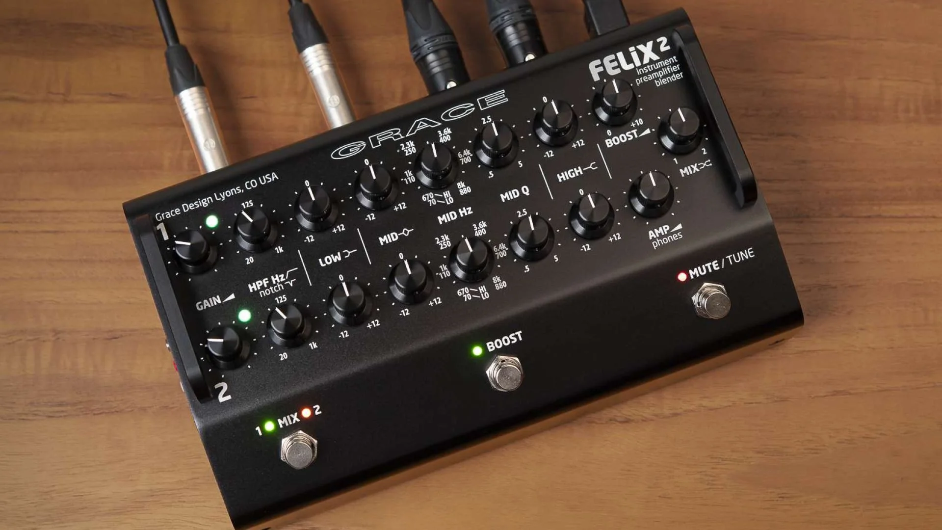 A black guitar effects pedal with multiple knobs, labeled 'GRACE" and 'FELIX2'. It has various controls for sound effects, including gain, notches, frequency, and boost. Connected to four cables, it is placed on a wooden surface.