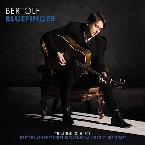 Cover of Bertolf's album "Bluefinger" featuring Bertolf sitting on an ornate chair playing an acoustic guitar, dressed in a black suit against a dark background.