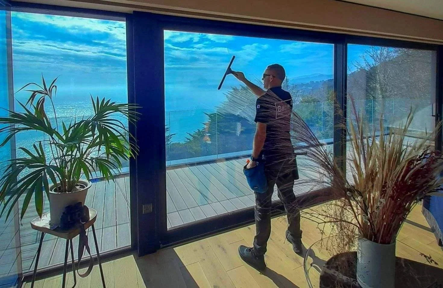 Base team member professionally cleaning the inside of large residential windows in Dublin using a squeegee.