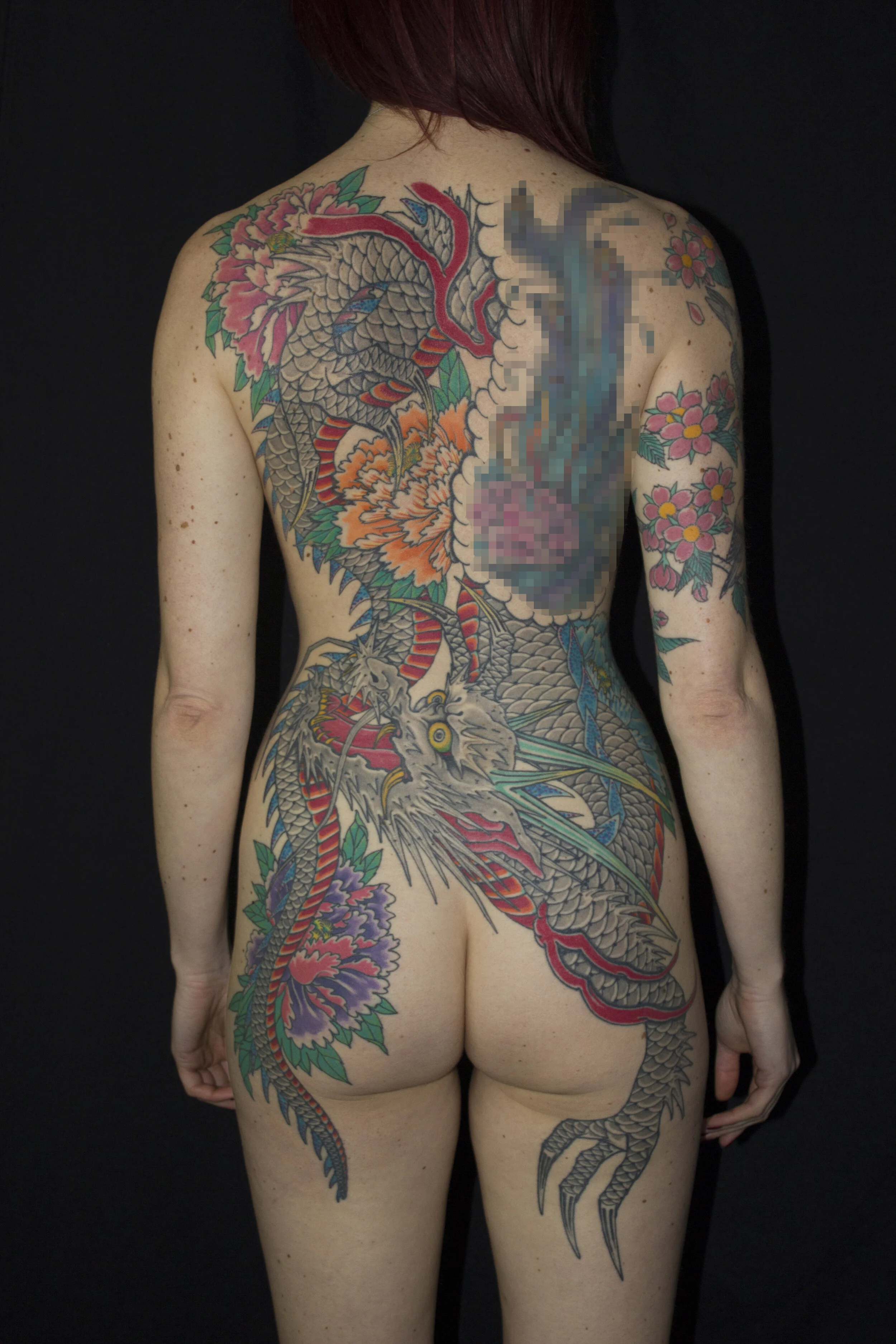 Large scale, bright and colourful Dragon back piece tattoo on a woman.