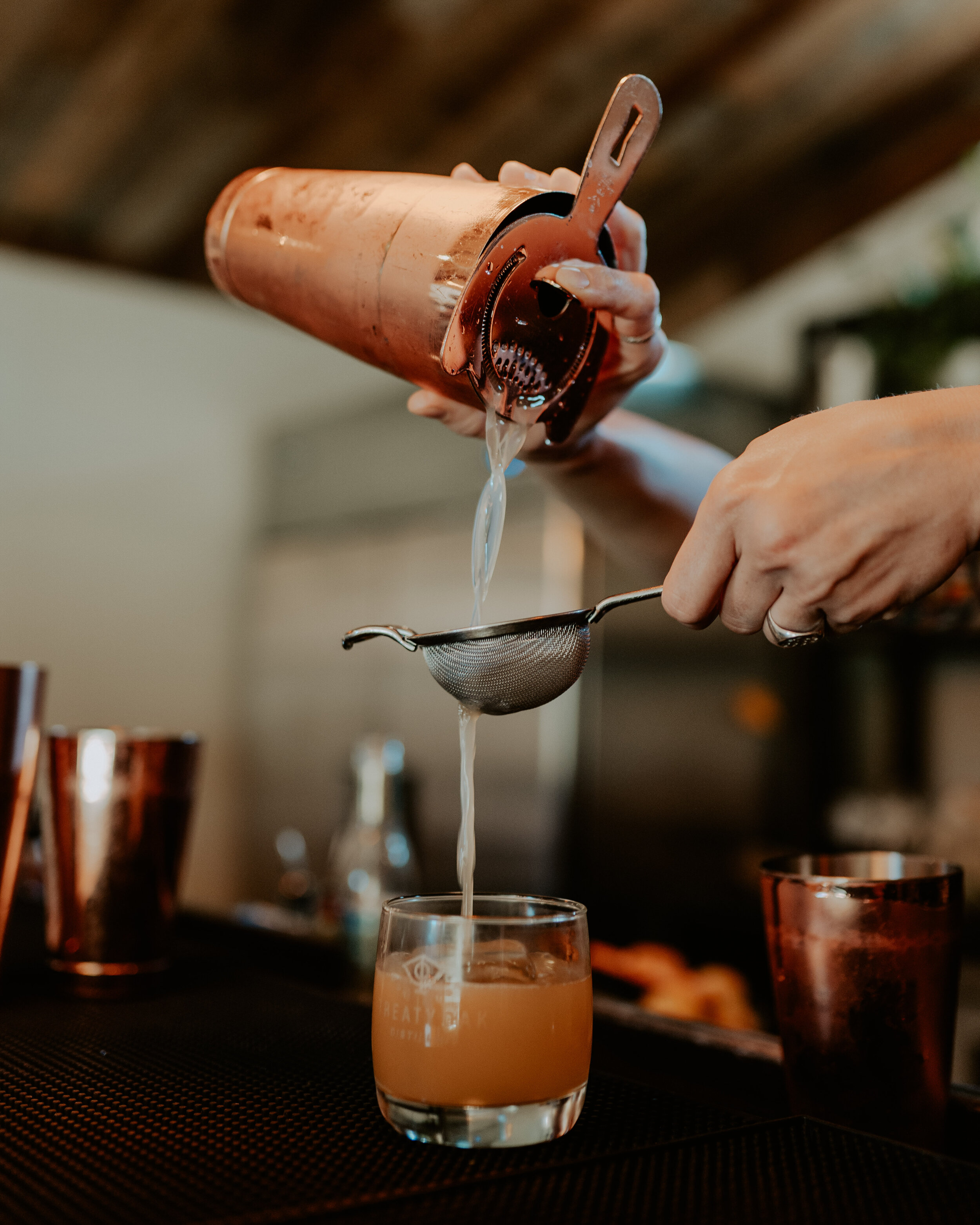 bartender pouring drink through strainer