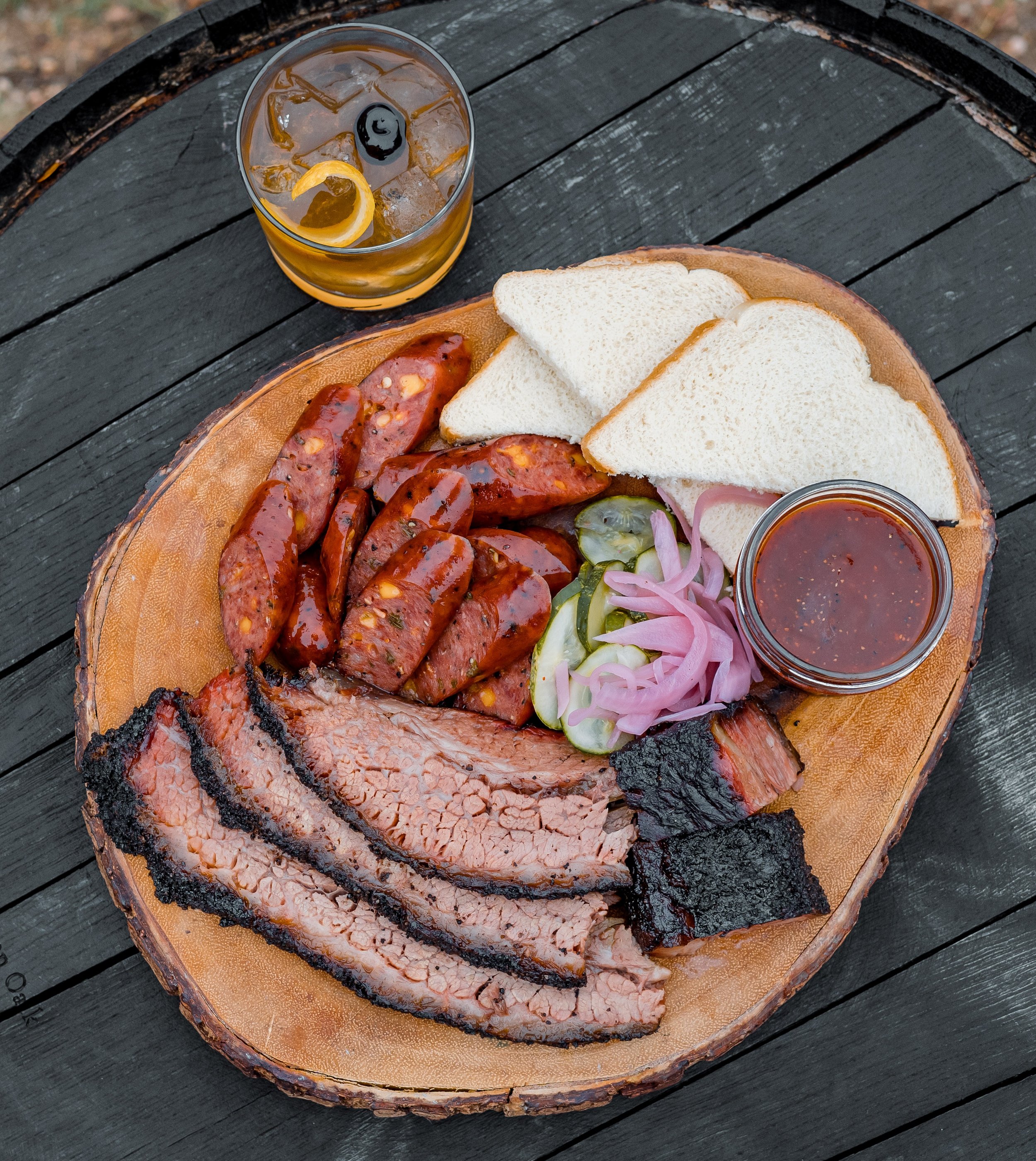 plate of brisket and sausage with bread and cocktail