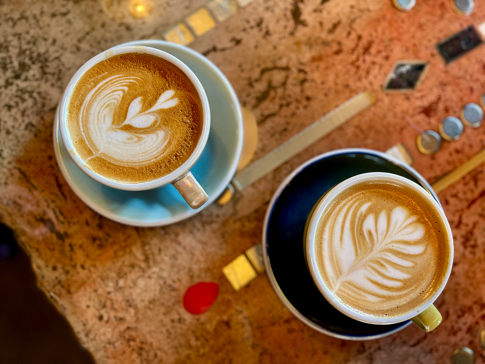Two lattes with latte art on a stone table