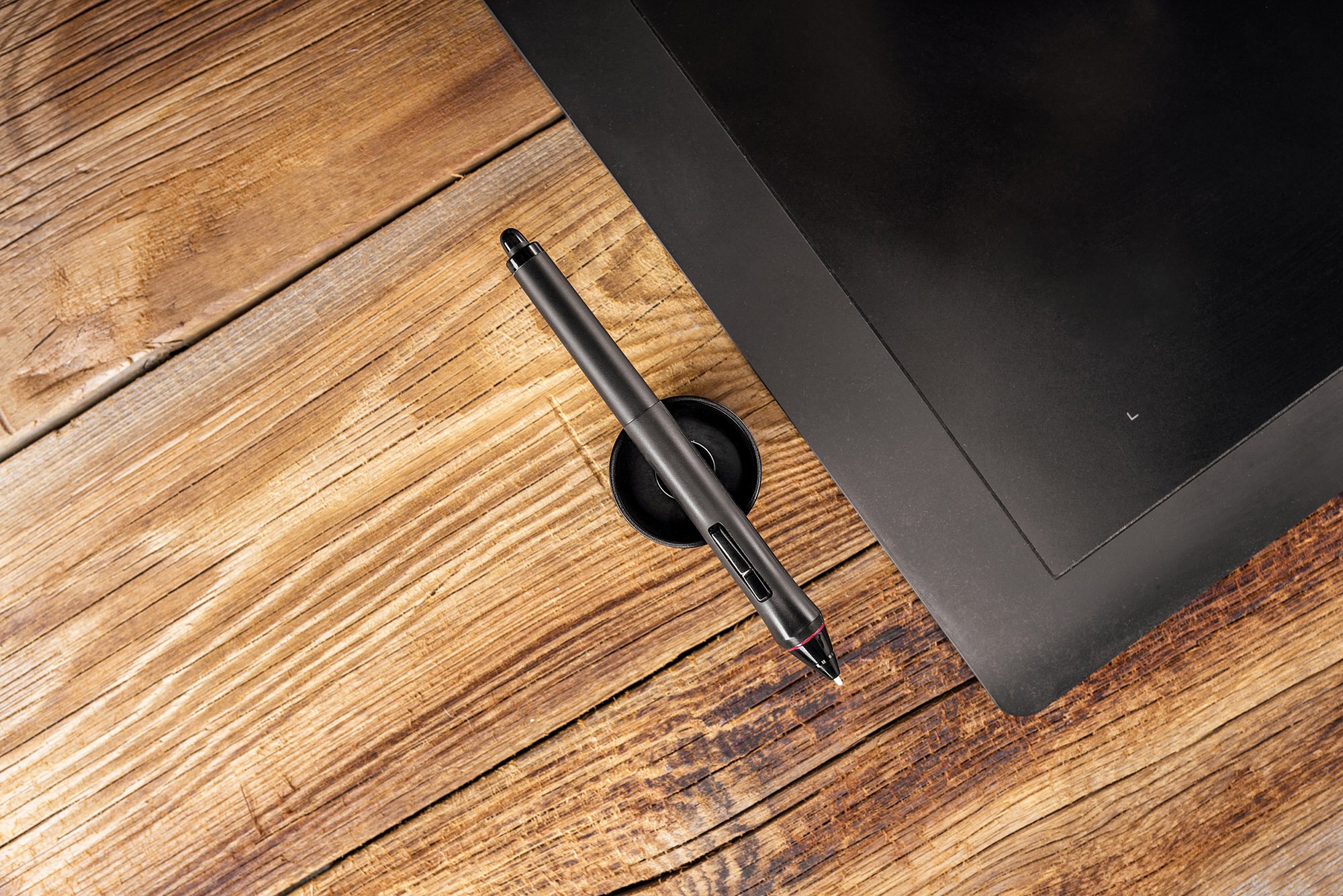  Topdown view of a tablet and stylus on a wooden table.  