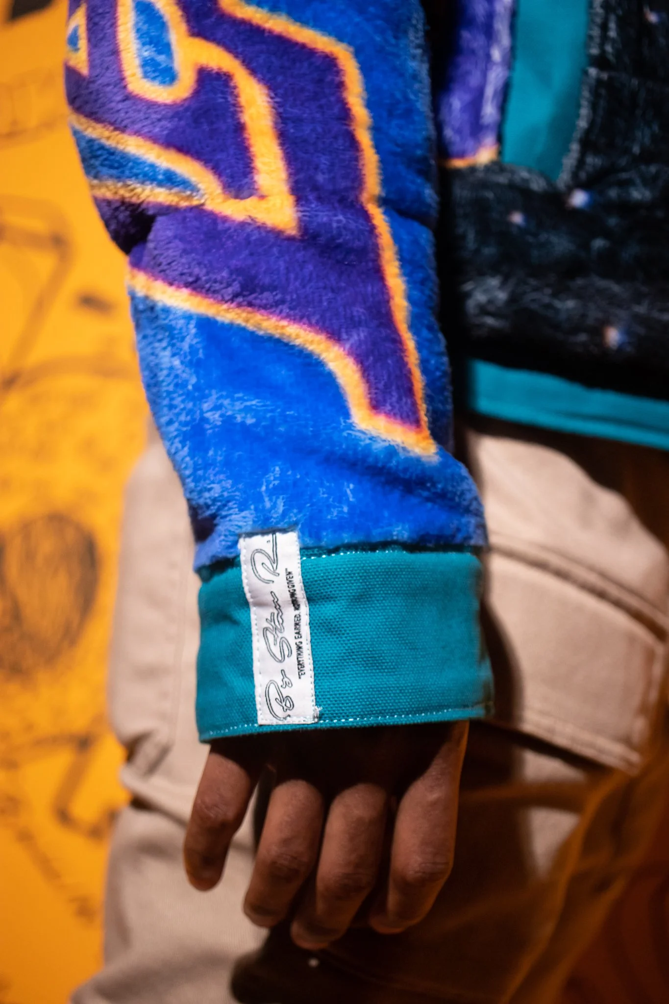  Close-up detail of the sleeve cuff, highlighting construction finish and integrated self-label branding. 