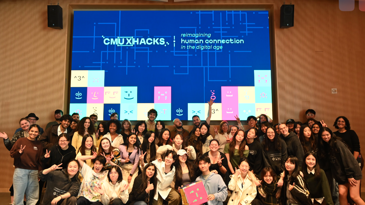 A picture of students before a projected sign that states CMU XHacks: Reimagining human connection in the digital age.