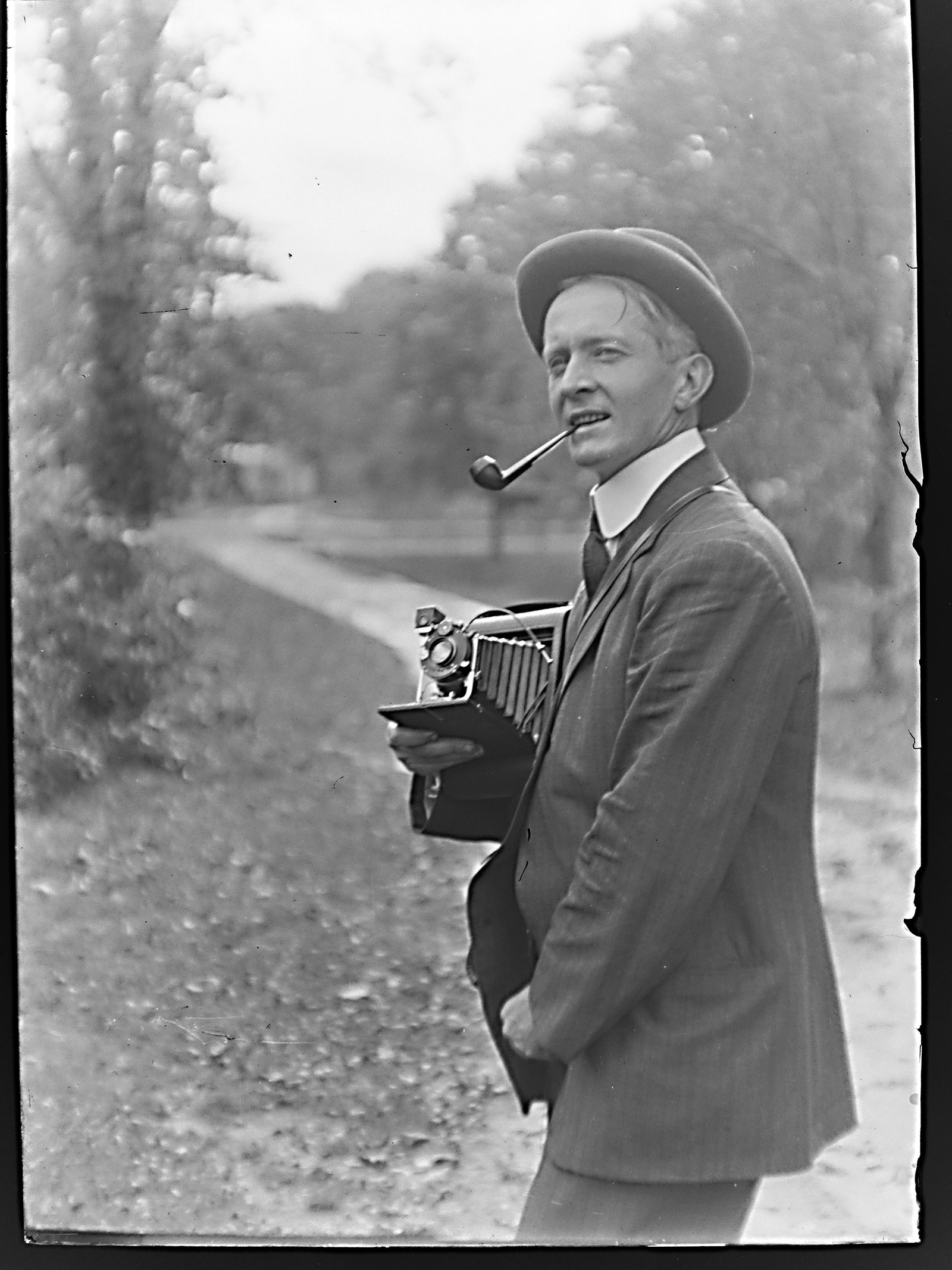 GN-078 Man with hat and pipe holding open camera.jpg