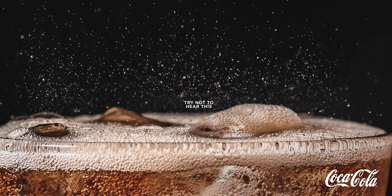 Exemplo de sinestesia. Anúncio impresso da Coca-Cola com bolhas efervescentes. Por DAVID The Agency. Disponível em <www.forbes.com/sites/willburns/2019/04/26/listen-to-these-new-print-ads-from-coca-cola/>. Acesso em 28 abr 2019.