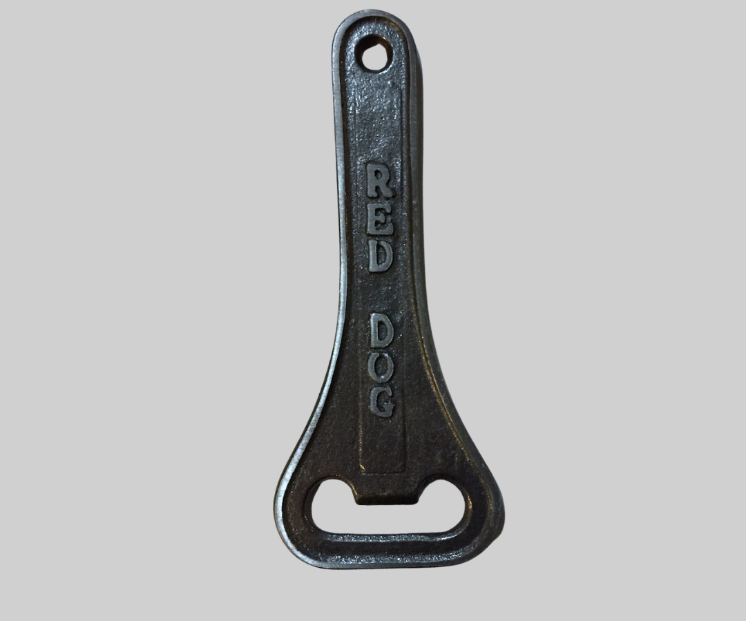 Large dark grey-brown bottle owner on light grey background. "Red Dog" is in large lettering down the handle of the bottle opener