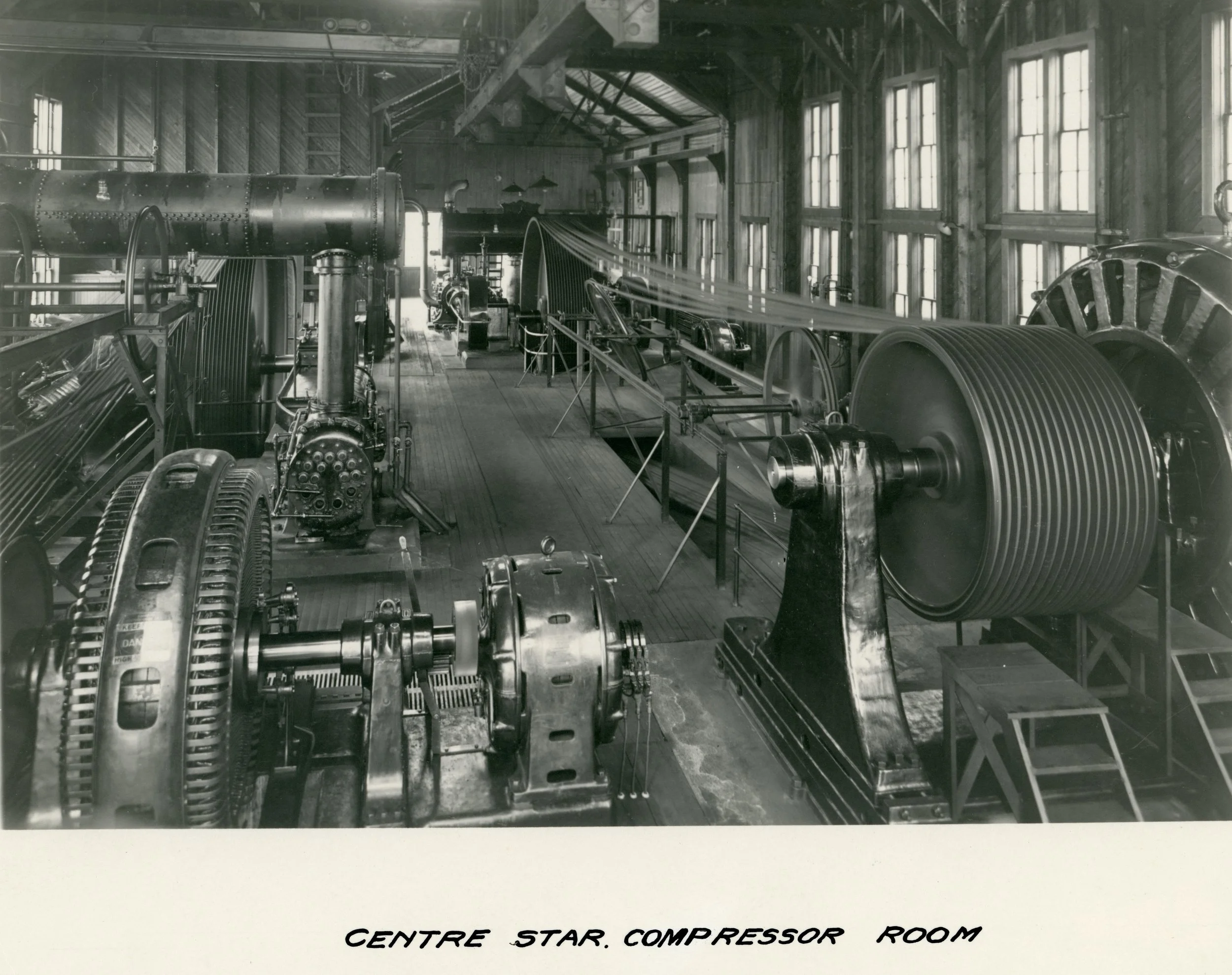 Photo 2304.0093: Compressor room at the Centre Star Mine. Note the same style of rope-driven compressor as seen on the lower grounds of the Museum.