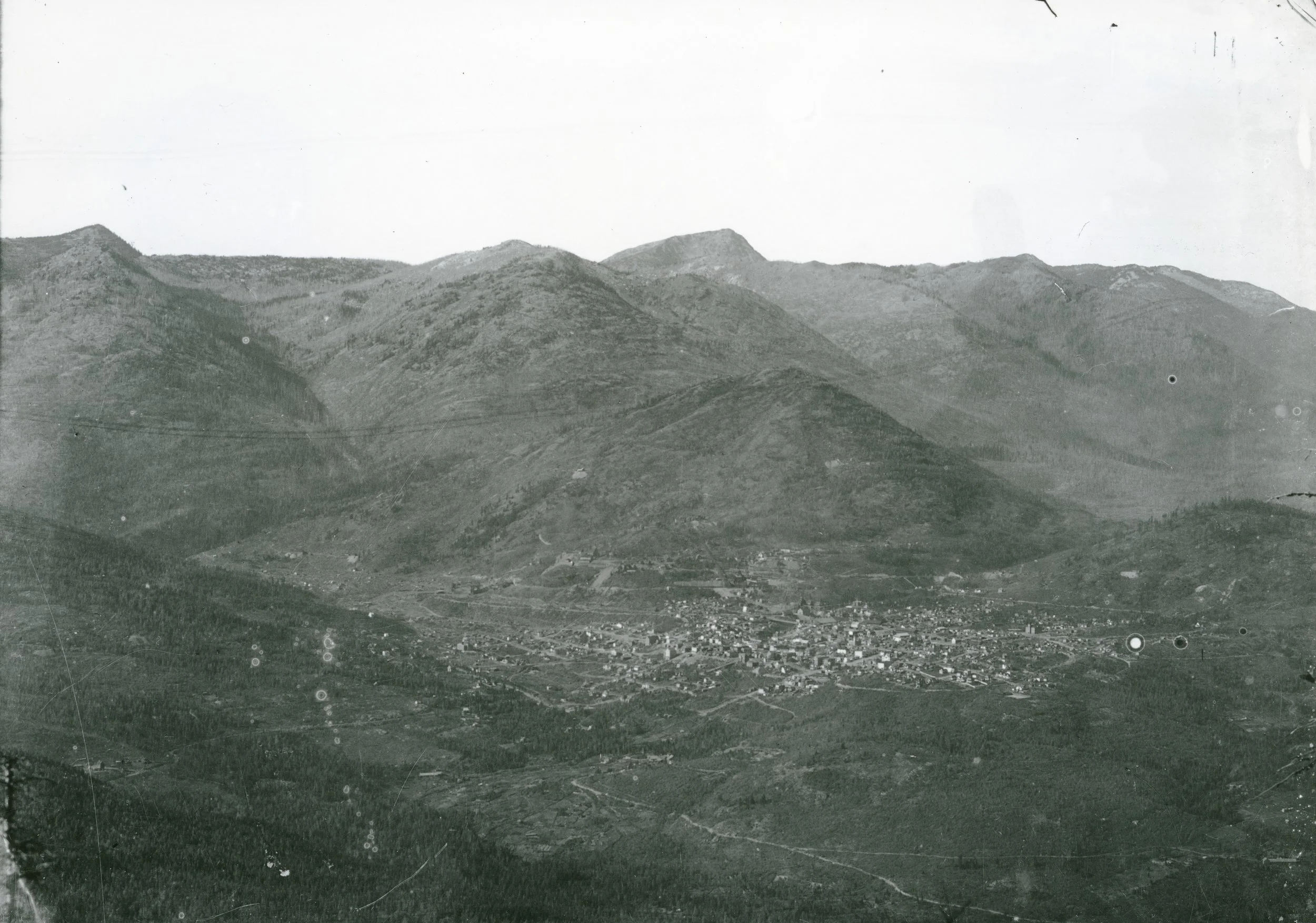 Photo 2311.0072: View of Rossland looking over the city from the south, circa 1902. Note the lack of trees on the surrounding mountains from the extensive logging operations.