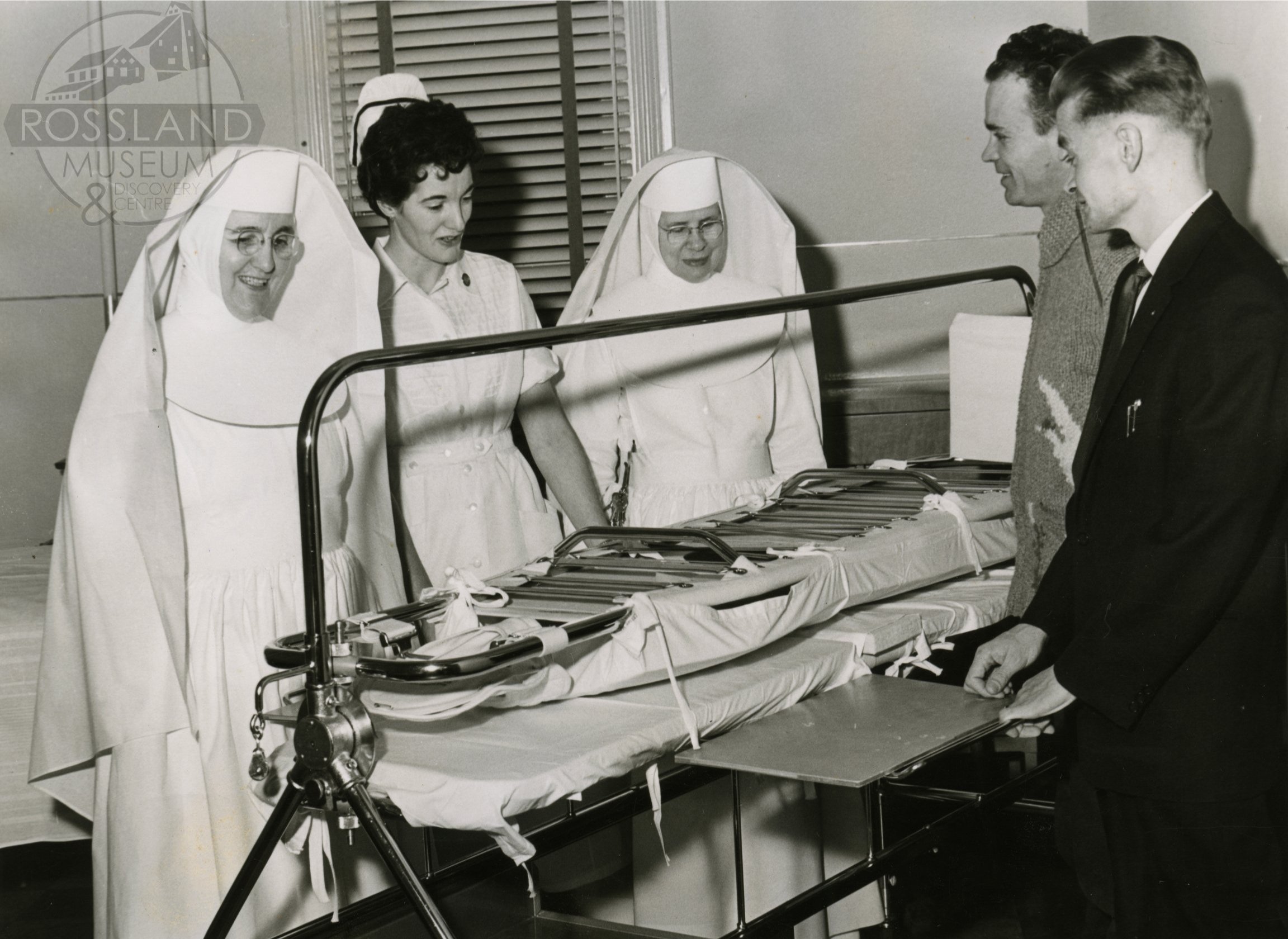   2276.0356 : Demonstration of new hospital equipment at Mater Misericordiae Hospital, January 23, 1958. Left to Right: Sister Angelo, Nurse Jean Barge, Sister Helena, "Sandy" Gordon, and Andy Chapdelaine of the Kinsman Club. 