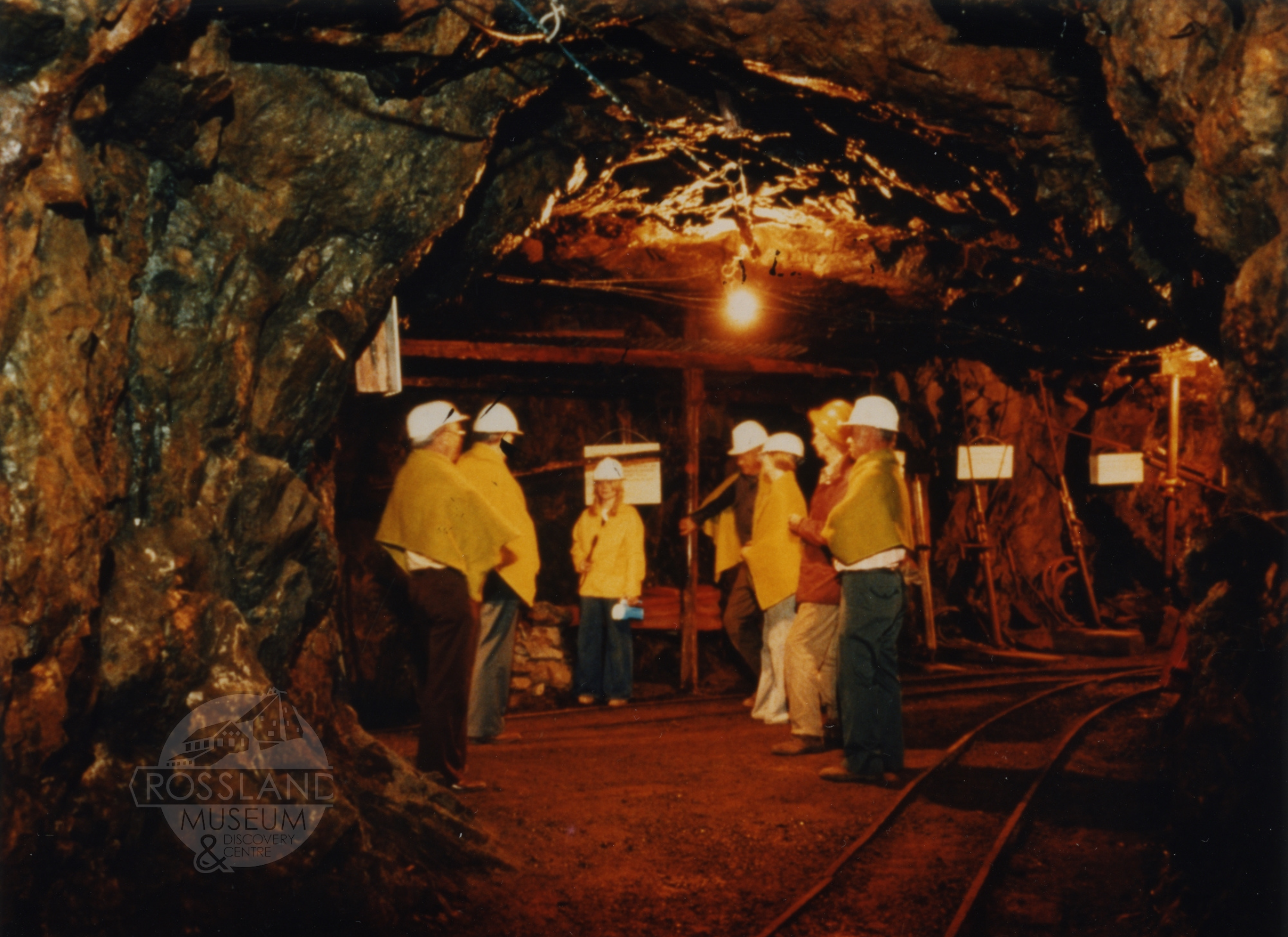 2276.0130: Group on an underground tour in the LeRoi Mine: Art Howard, J.D. McDonald, tour guide Carmen Godson, Smitty, Mavis Mitchell, Roger Terhune and Jack Page, circa 1978