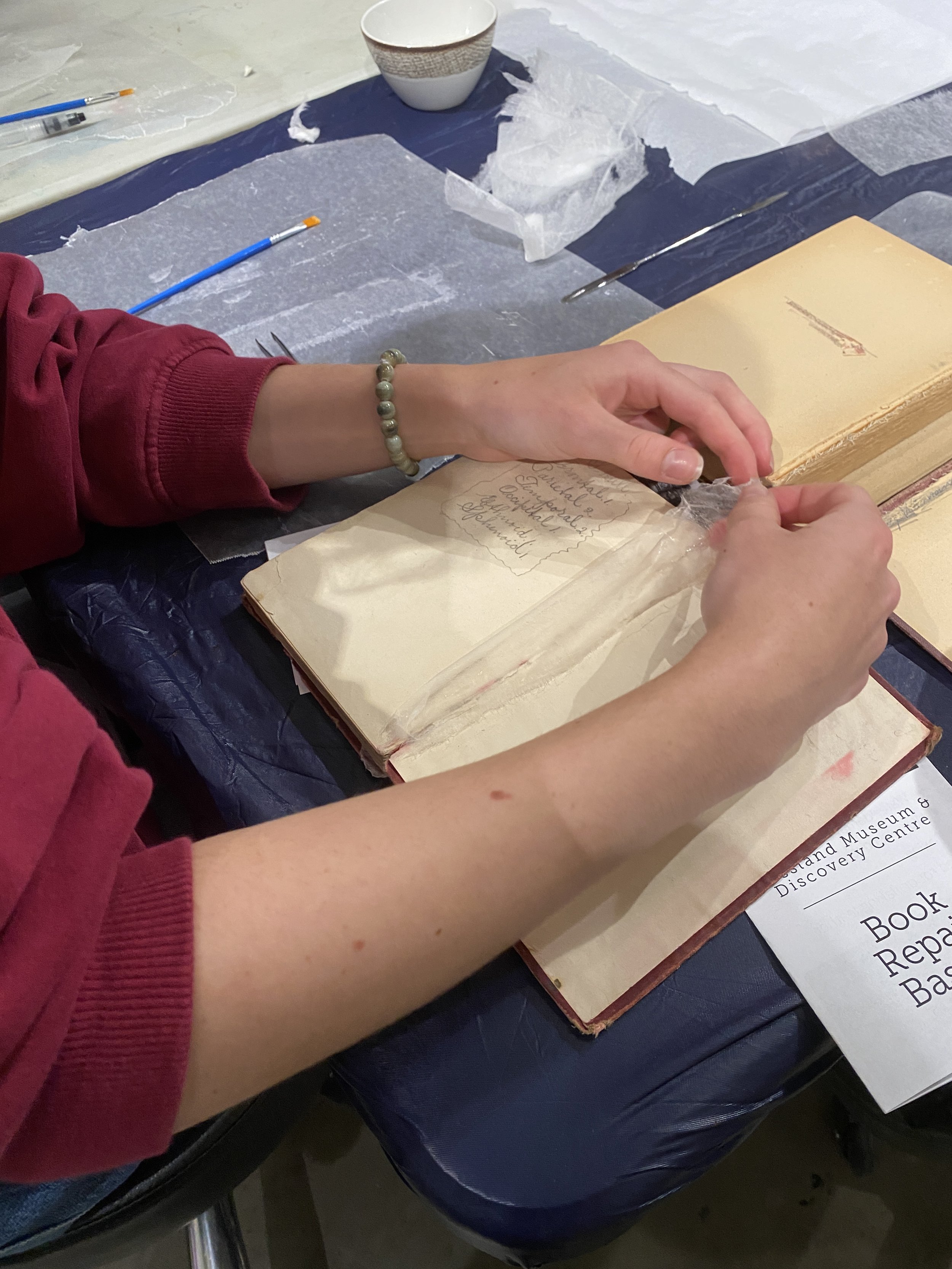 Erin working on repairing a book during a student skills workshop