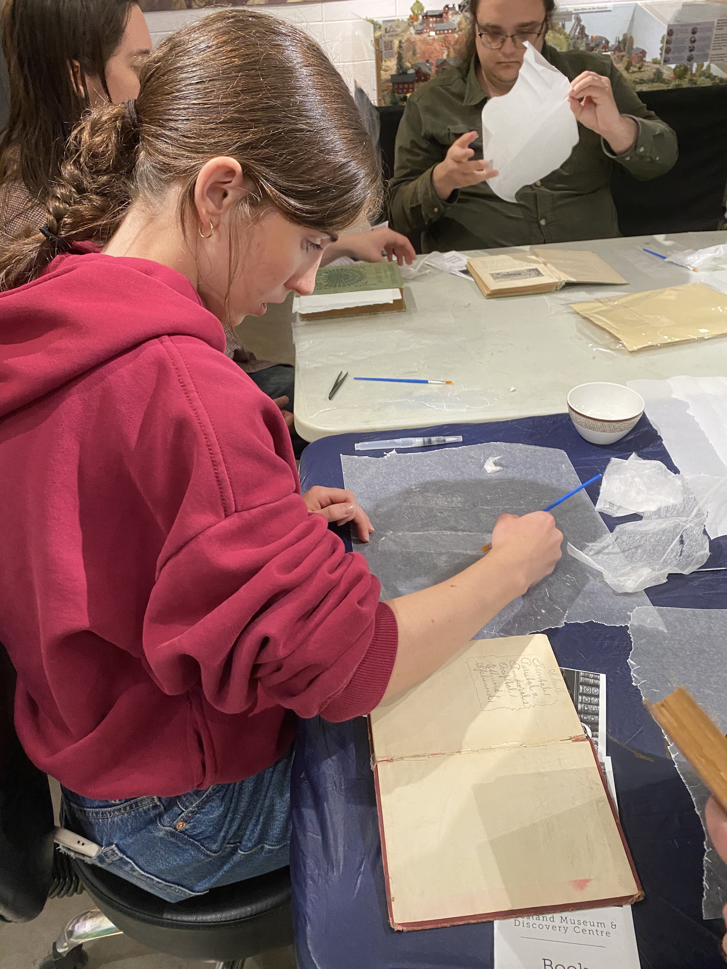 Erin working on repairing a book during a student skills workshop