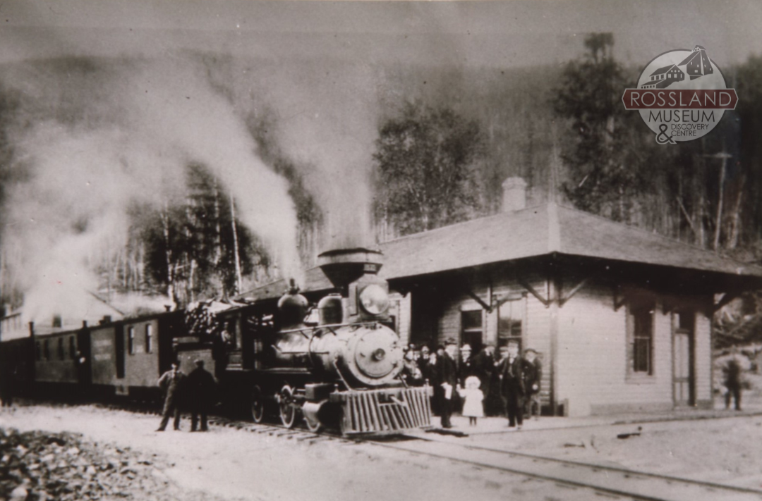 Black and white photograph of a steam train at a train station