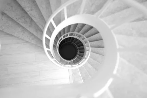 Black and white photo looking down a spiral staircase, evoking the disorientation of dizziness