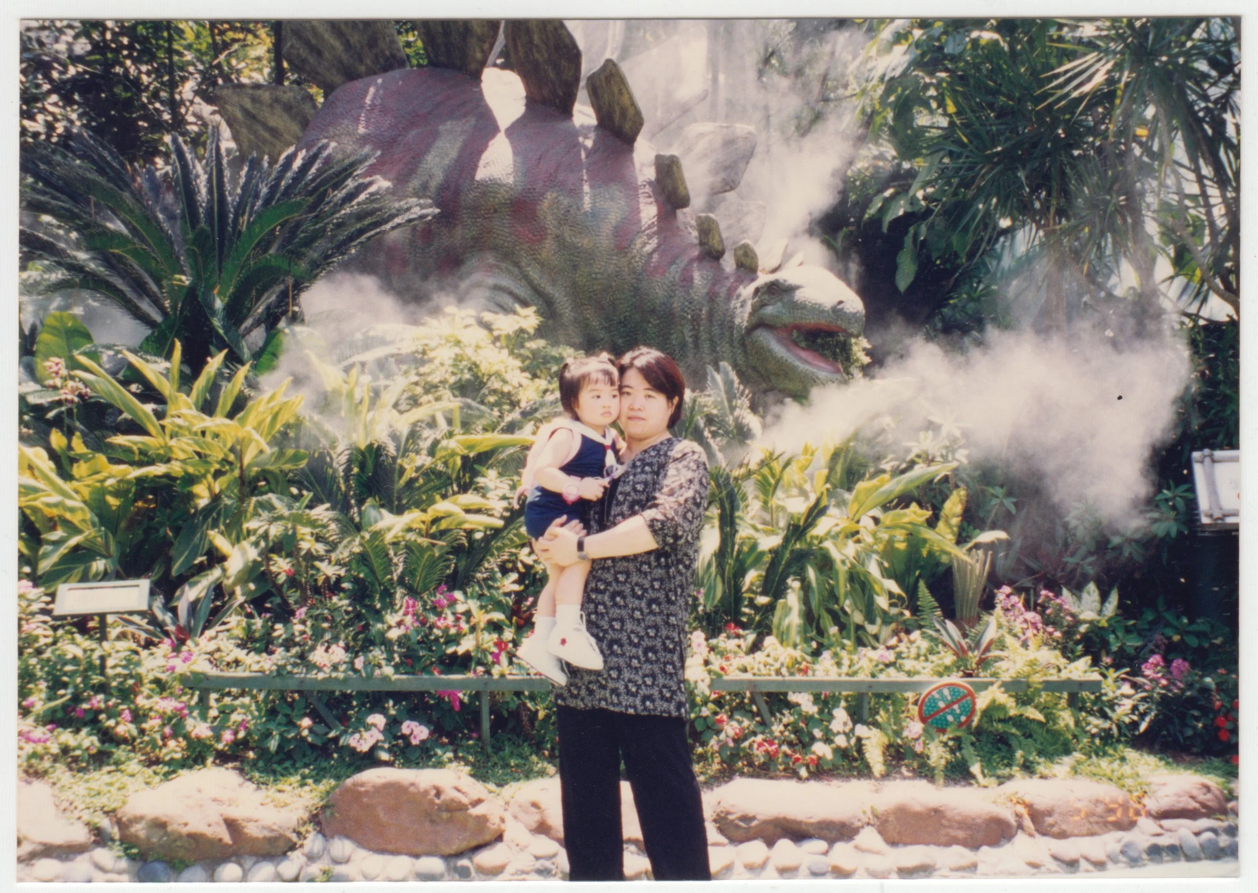 Mum & Charlotte in a park with a stegosaurus installation, c. September 1997.