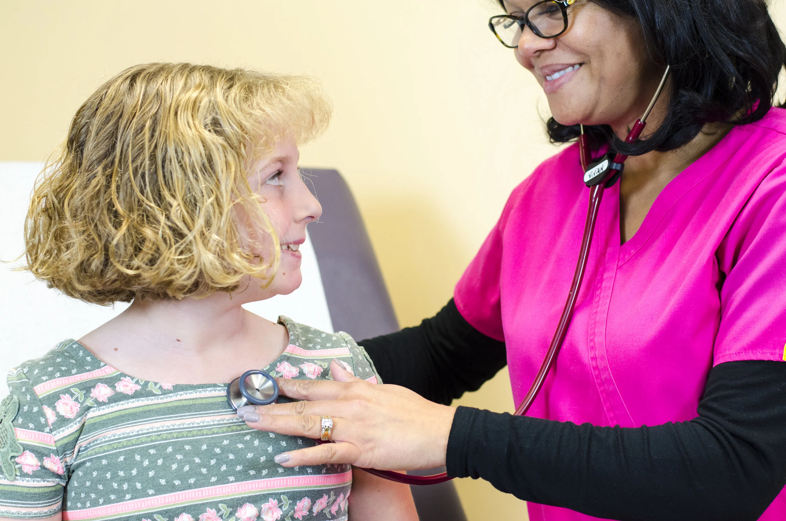 Female doctor in pink scrubs and young girl patient