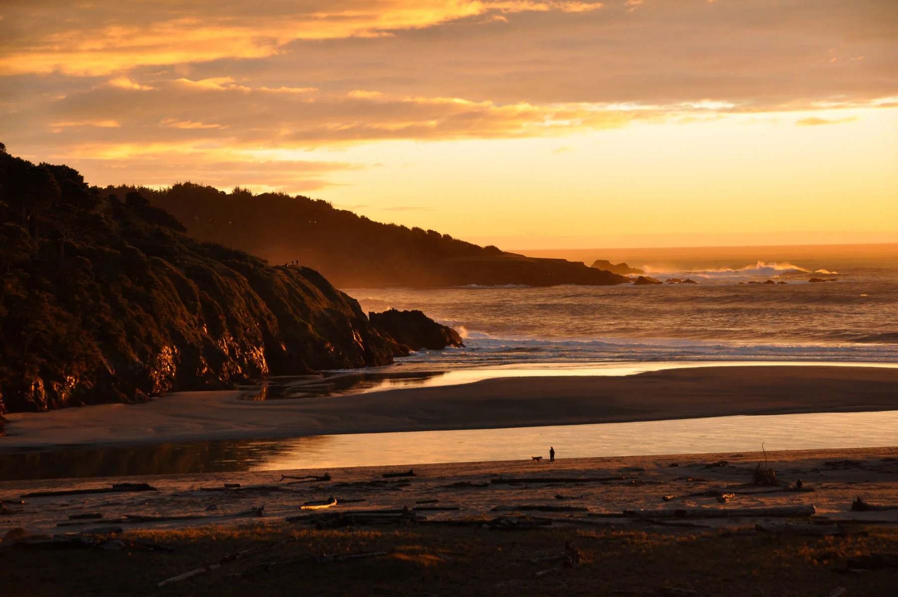 sunset lights the ocean gold as retreating waters shimmer on the beach across from Brewery Gulch Inn