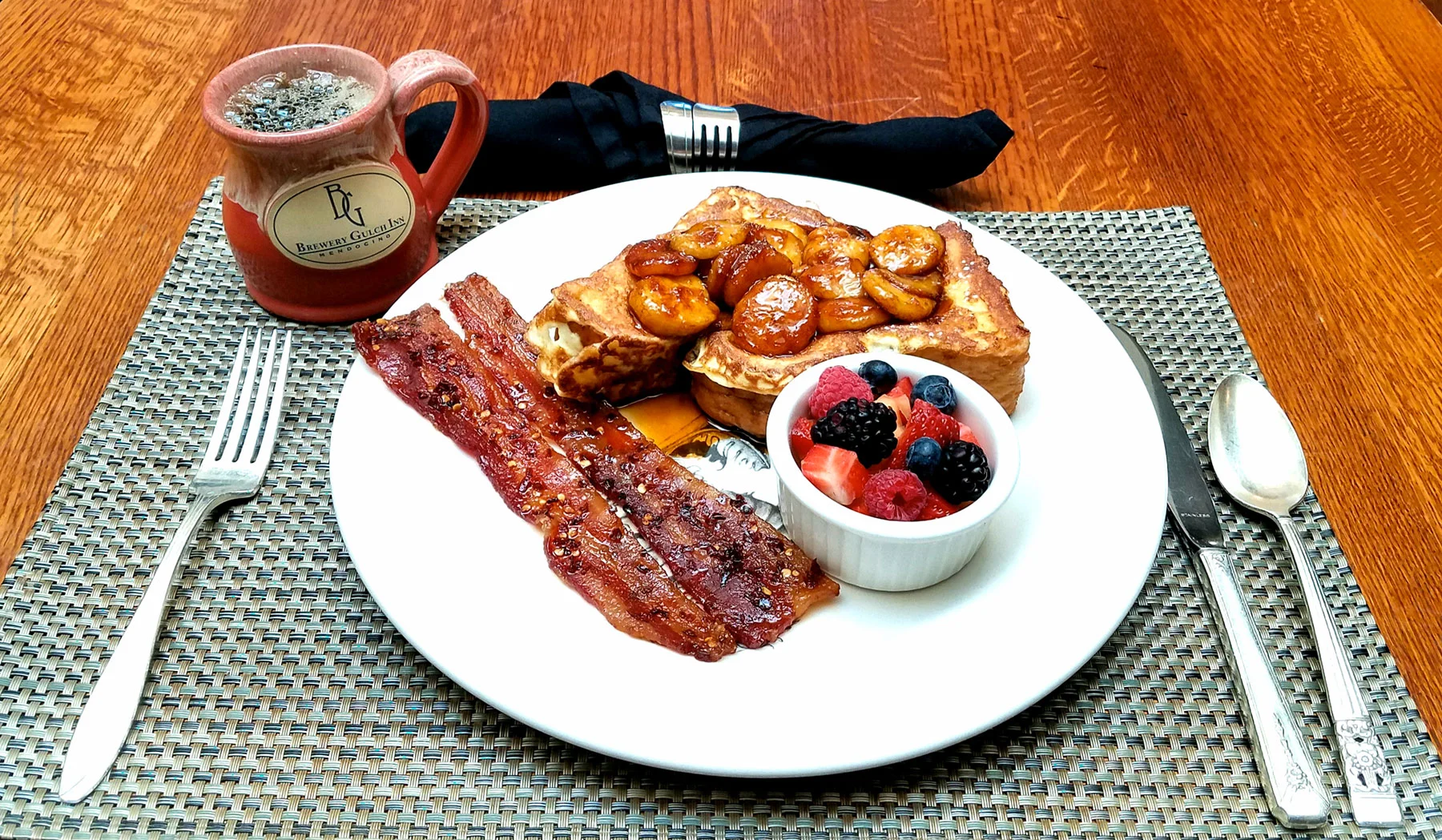 French toast with bananas, bacon, fruit and coffee.